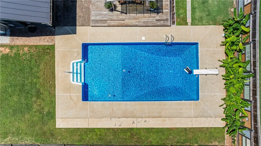 An inviting in-ground pool, complete with a diving board and ample decking, provides a perfect outdoor oasis.
