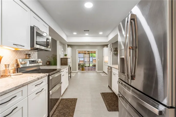 Modern kitchen with sleek stainless-steel appliances and abundant natural light from the sliding glass doors.