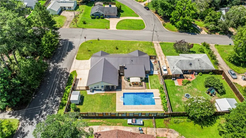An aerial perspective reveals a private pool with a diving board, surrounded by a spacious patio, offering abundant space for outdoor activities and relaxation.