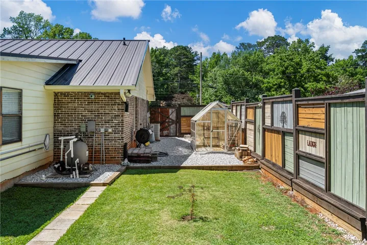 A private yard with a compact greenhouse offers a dedicated space for gardening enthusiasts.