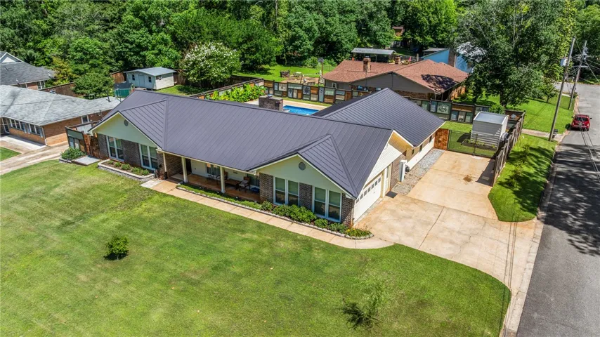 A sprawling estate boasting a new metal roof, lush front yard, and an inviting private pool.