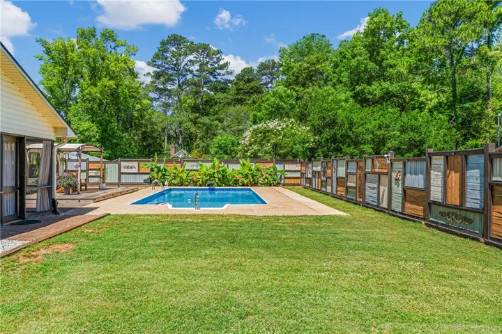 A private backyard oasis features a glistening pool and a lush lawn, enclosed by a unique artistic fence.
