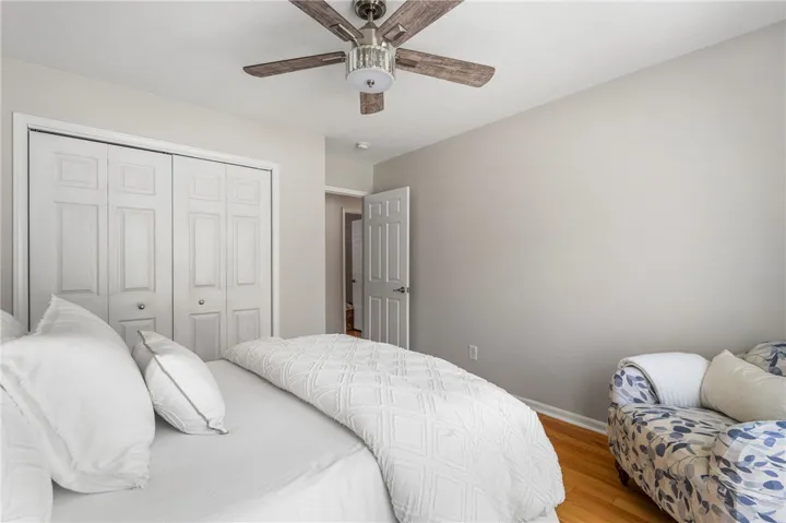 An inviting bedroom features warm wood flooring and a stylish ceiling fan with integrated lighting.