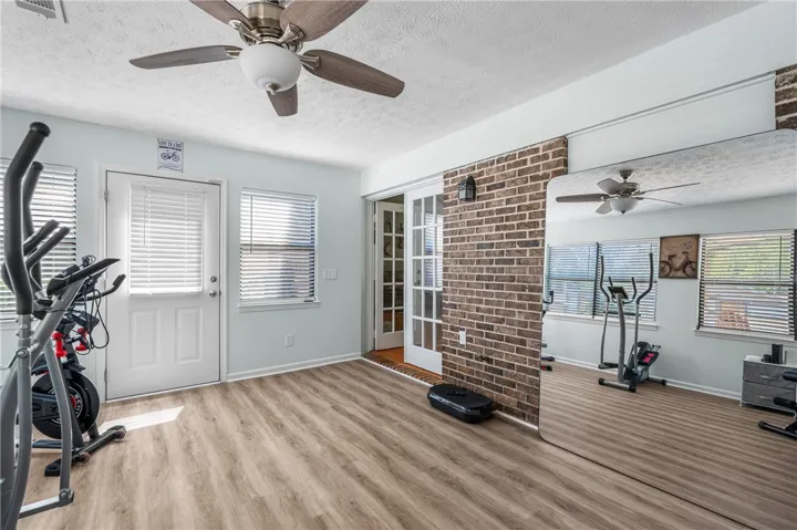 An inviting flex space features a ceiling fan, durable flooring, and French doors to another room.