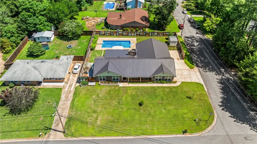 An aerial perspective reveals a charming residence with a metal roof and a sparkling backyard pool.