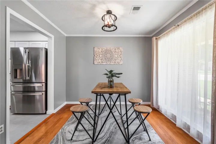 Hardwood floors and ample natural light define this inviting dining space, flowing into a modern kitchen.
