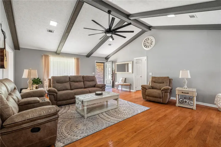 A comfortable living space boasts high vaulted ceilings with exposed beams and rich hardwood flooring.