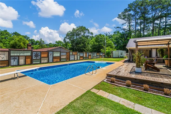 An inviting backyard oasis offers a pristine pool alongside a spacious wooden deck, ideal for outdoor leisure.