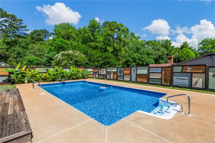 A spacious in-ground pool offers a refreshing oasis, privately enclosed by a unique decorative fence.