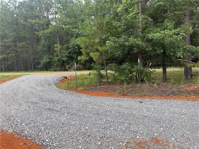 A winding gravel driveway carves a path through the verdant landscape, leading to a private woodland retreat.