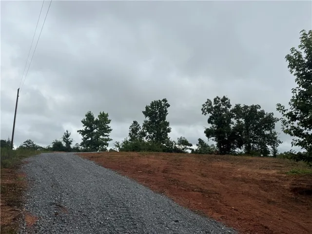 A prime build site awaits, offering a clear expanse and verdant trees under a vast sky.