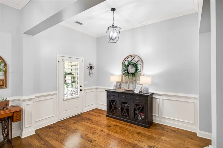 Natural light illuminates rich hardwood flooring and classic wainscoting, creating a welcoming entrance.