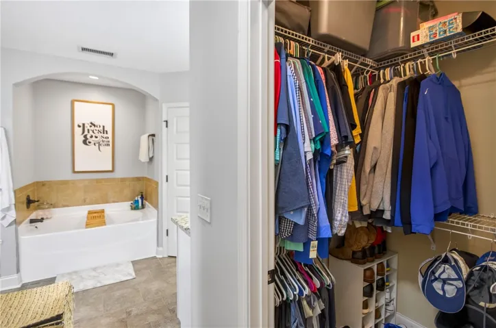 A well-appointed bathroom offers a deep soaking tub adjacent to a spacious walk-in closet.