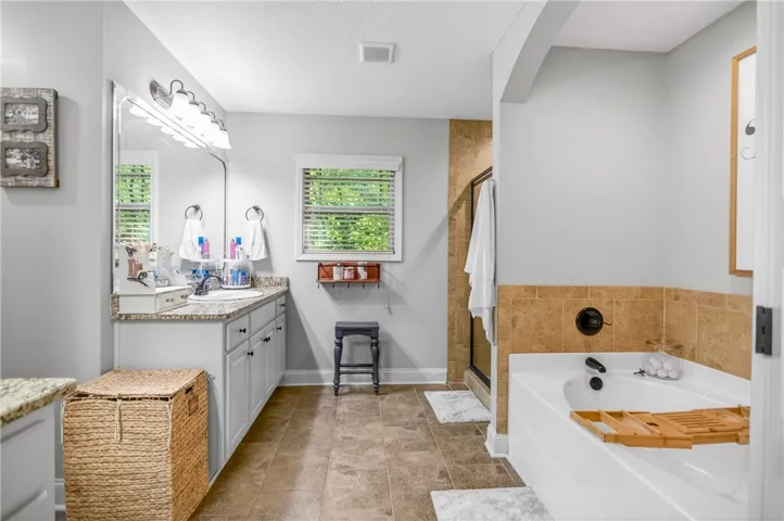 A well-appointed primary bathroom features a generous soaking tub and tiled walk-in shower.