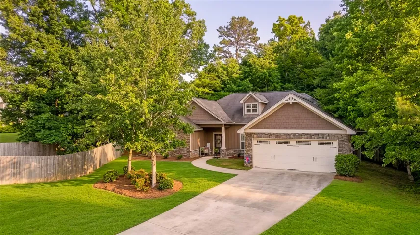 A welcoming stone and shake exterior provides excellent curb appeal, nestled amongst verdant landscaping.