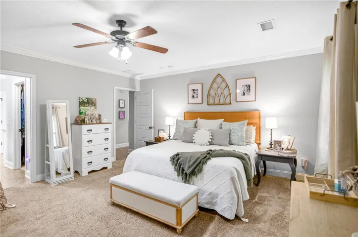 Relax in this well-lit primary bedroom, complete with a cozy ceiling fan and plush carpet.