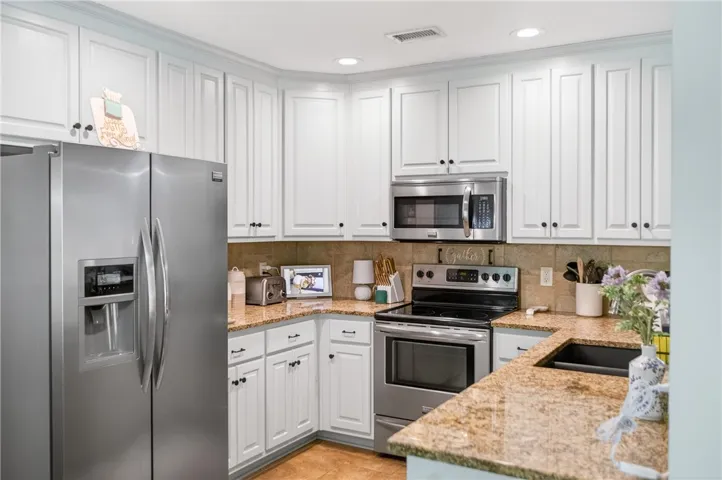 White cabinetry, granite counters, and stainless steel appliances complete this well-appointed kitchen.
