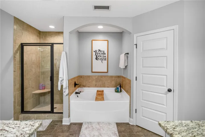 Luxurious soaking tub and tiled walk-in shower elevate this pristine primary bath.