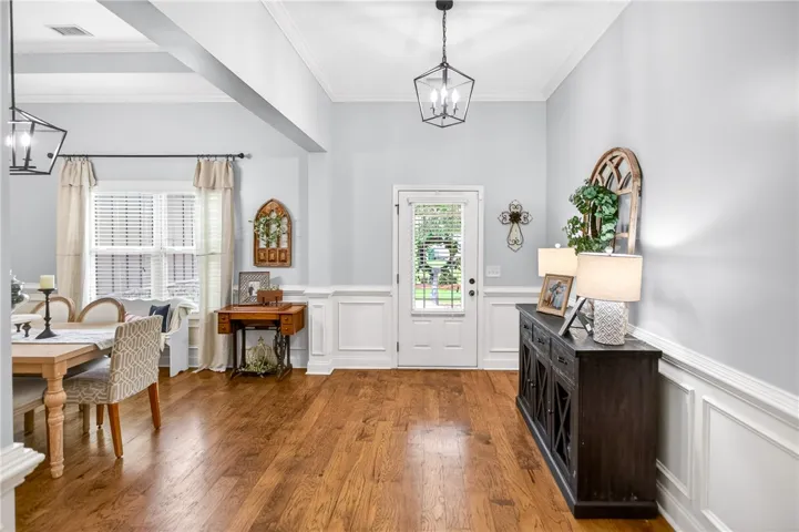 Hardwood floors stretch across this entry hall, featuring high ceilings and detailed crown molding.