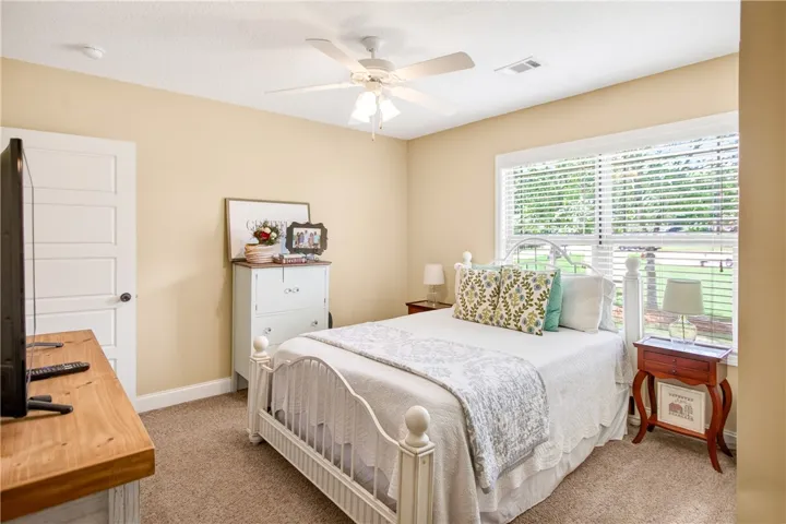 A well-lit bedroom features plush carpeting and a convenient ceiling fan for ultimate comfort.