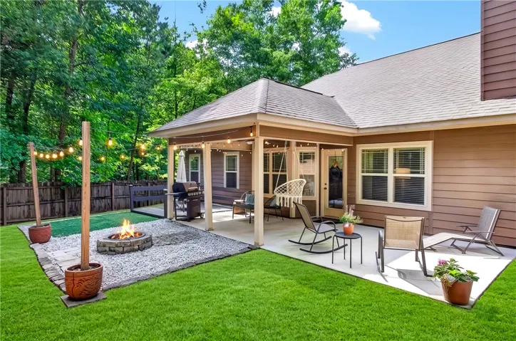 An inviting backyard oasis offers a fire pit, covered patio, and lush green space for entertaining.