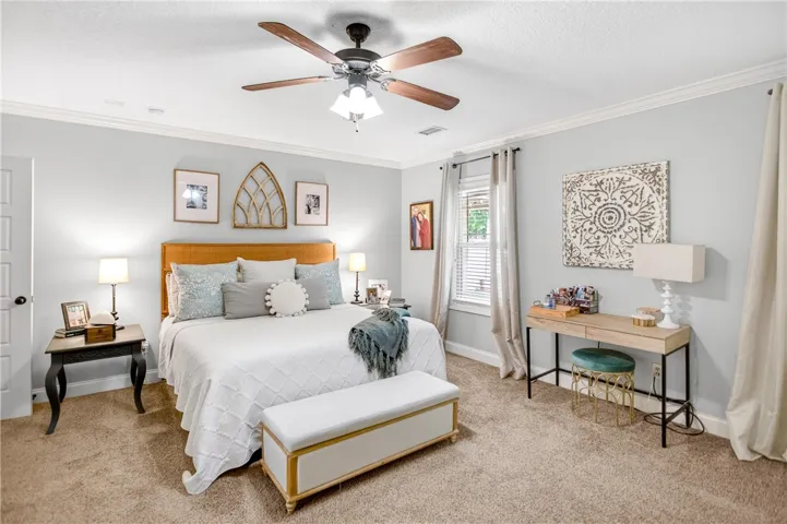 A comforting bedroom space featuring crown molding and a ceiling fan, creating an inviting retreat.