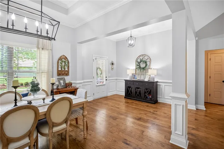 Hardwood flooring extends throughout this generous dining room, illuminated by a contemporary chandelier and natural light.