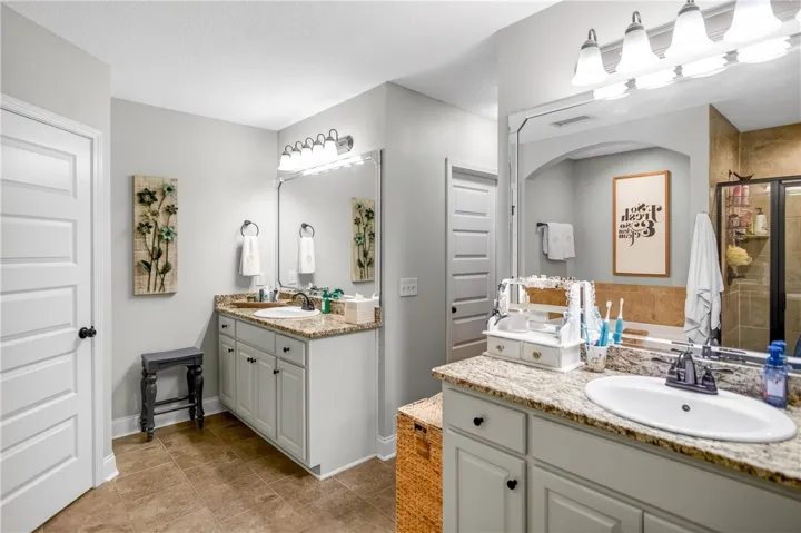 Granite counters and dual vanities provide abundant space in this light-filled primary bathroom.