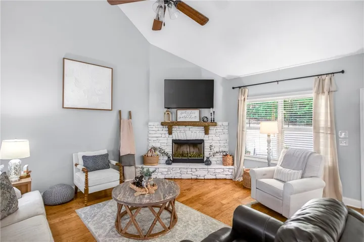 A whitewashed brick fireplace forms the focal point in this inviting living area, complemented by rich hardwood floors.