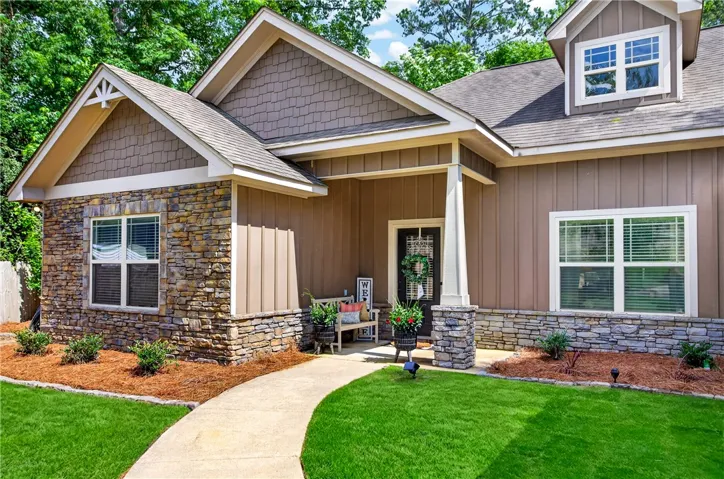 A welcoming stone and wood-sided facade with a lush green lawn and charming front porch.