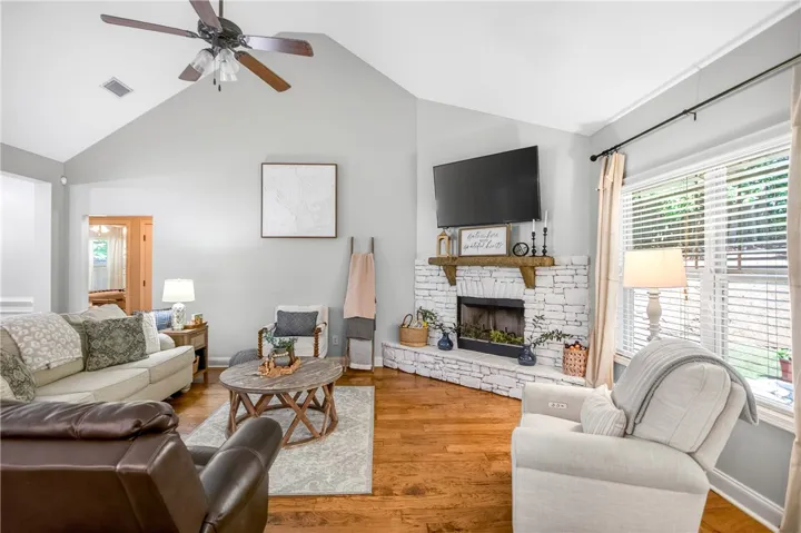 A corner fireplace crafted from painted stone anchors this warm and inviting living area with rich hardwood flooring.