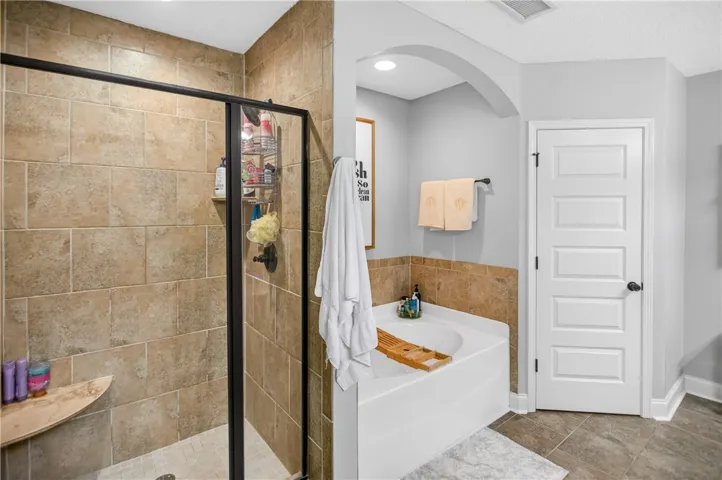 Indulge in a primary bathroom featuring a spacious walk-in shower and a corner soaking tub.