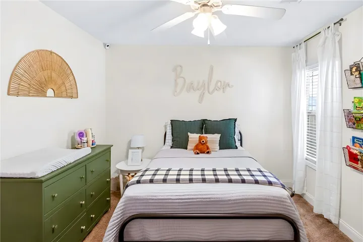 A well-lit room showcases carpet flooring, a ceiling fan, and a single window, providing comfort and natural light.