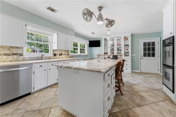 Culinary delights await in this bright kitchen, complete with a generous marble island and built-in display cabinetry.