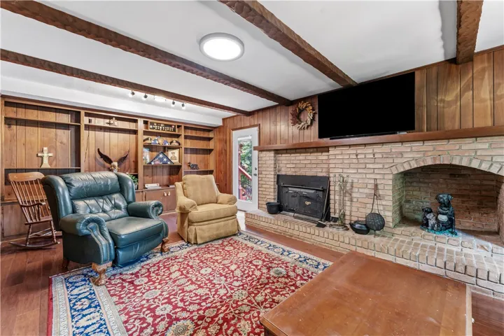 Rich wood paneling and exposed beams frame a brick fireplace, creating a warm, inviting atmosphere.
