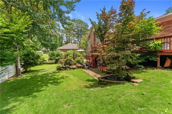 A verdant lawn frames a tiered outdoor living space, leading to a charming brick residence.