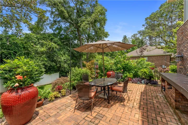 A private backyard oasis features a brick patio, mature landscaping, and an outdoor entertaining area.