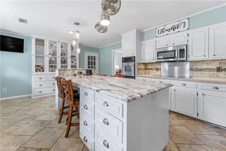 This kitchen showcases a central island with sleek stone countertops and integrated storage.