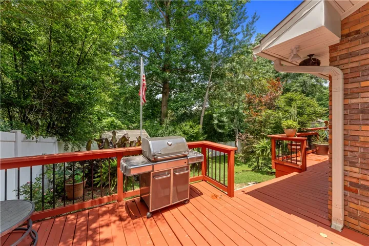A spacious wooden deck provides ample room for outdoor entertaining amidst lush, verdant trees.