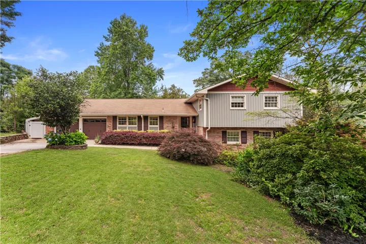 A classic brick and siding home, nestled amidst mature trees and meticulously maintained landscaping.