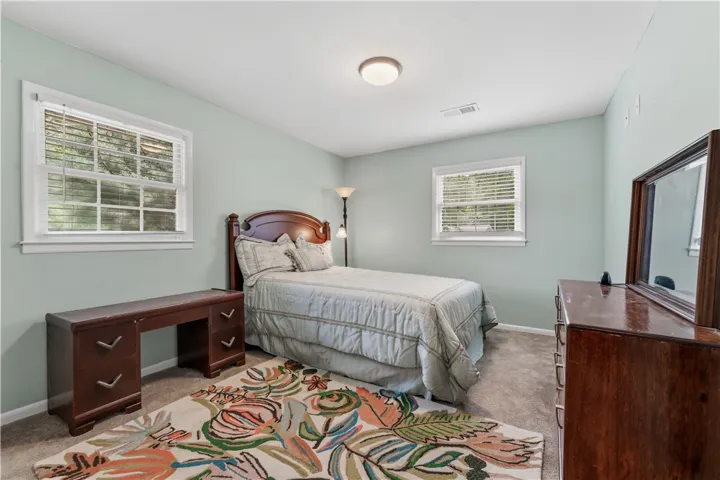 A tranquil bedroom provides a restful retreat with soft wall colors and dual windows.