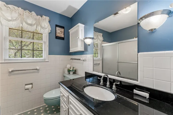 A well-appointed bath features a tiled vanity with a sleek black countertop and built-in sink.