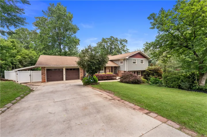 A well-maintained home featuring a two-car garage, lush lawn, and mature trees, offering a welcoming curb appeal.