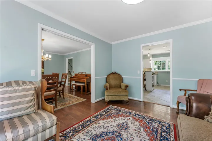 Hardwood floors and crown molding define this versatile interior space, flowing into a dining area and kitchen.