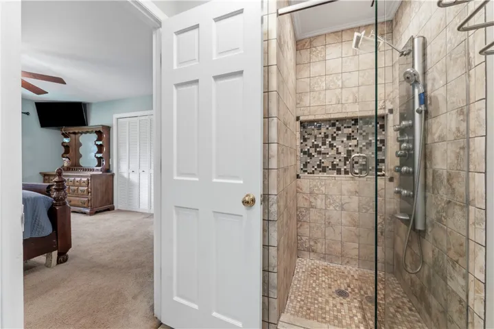 A tiled walk-in shower features a modern multi-jet panel and a mosaic accent niche.
