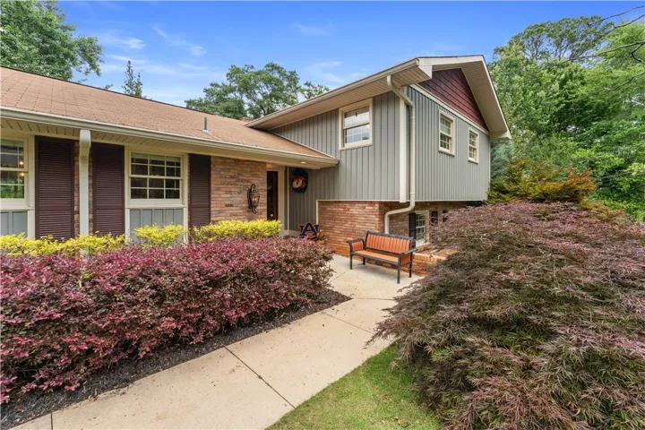 A charming brick and siding facade welcomes, surrounded by mature, verdant landscaping.