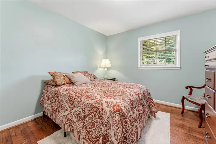 Hardwood floors and a tranquil window view complete this peaceful bedroom.