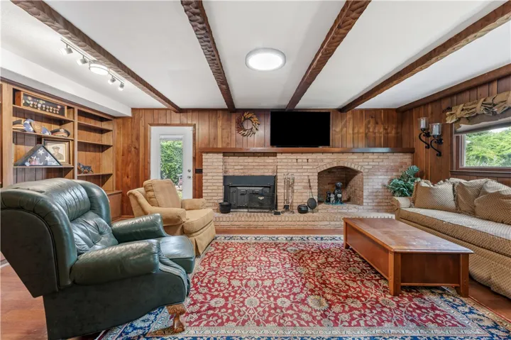 Warm wood paneling and a brick fireplace create an inviting, rustic living space.