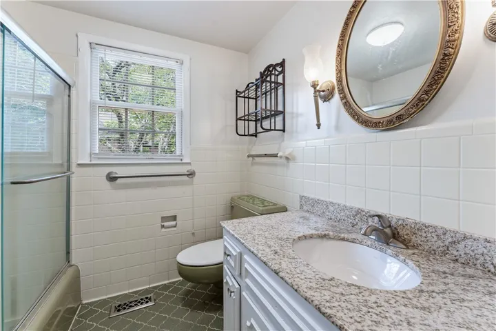 A well-lit bathroom with patterned tile flooring and a sleek granite vanity.