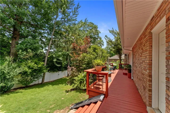 A spacious red deck with surrounding greenery offers a serene outdoor living space.